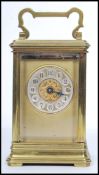 An early 20th century brass carriage clock hacing gilded face with enamel button numerals with