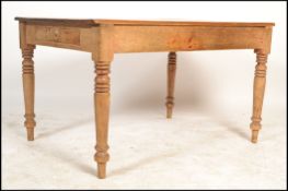 A Victorian pine country dining table being raised on turned legs with fitted frieze having single