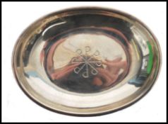 A silver hallmarked pin dish of oval form with a central  chased design of swords, dating to 1973,
