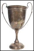 A hallmarked silver large trophy cup raised on a stepped circular base with scrolled twin handles to
