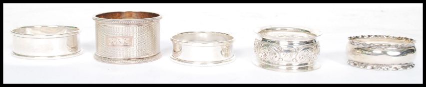 A collection of five silver hallmarked non - matching napkin rings in various shaped and styles
