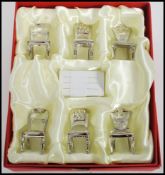 A set of six silver white metal name place holders in the form of 19th century chairs. Measures 5.