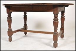 An early 20th century oak extending dining table of oval form being raised on turned legs united
