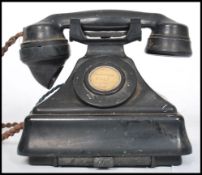 A vintage 20th century bakelite ring dial telephone. Raised on a square plinth base with sloped