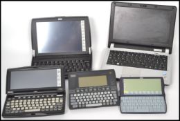 A collection of early 21st century electronic note pad computers to include Psion all with leads.
