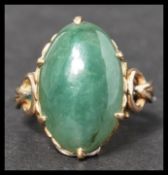 An 18k gold stamped vintage jade ring. Having a large jade cabochon with stylised shoulders. Stamped