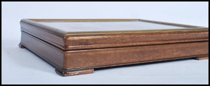 A 20th century table top oak glazed display case, hinged top with gilt border to the glazed