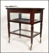 An unusual mid century mahogany and glass bijouterie display cabinet trolley. Raised on castors to
