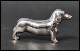 A cast sterling silver figure of a sausage dog. Marked Sterling. Measures 4cms. Weight approx 14.8g.