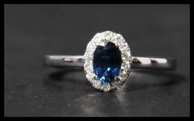A hallmarked 18ct white gold sapphire and diamond ring having a central oval cut sapphire surrounded