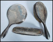 A silver hallmarked three piece brush and mirror set by Henry Matthews bearing Birmingham