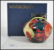 A Moorcroft ceramic vase tube lined decorated with flowers in the Queens Choice pattern complete