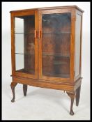 A 1930's Art Dec oak bookcase display cabinet having shaped cabriole legs with twin doors housing