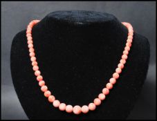 A vintage angel skin coral necklace. The necklace of graduating form each bead carved and strung set