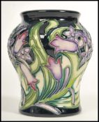 A Moorcroft ceramic vase tube lined decorated with flowers in the Isis pattern complete in