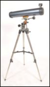 A vintage 20th century Celestron AstroMaster 76 telescope raised on an adjustable tripod base.