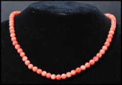 A vintage angel skin coral necklace. Each bead carved and strung set to a gilt barrel clasp.