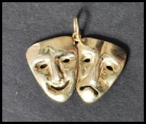 A 9ct gold pendant in the form of comedy and tragedy masks having circular bail hoop atop. Stamped