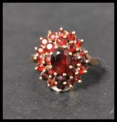 A hallmarked 9ct gold garnet stone cluster ring. The central stone adorned with two layers of garnet