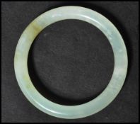 A Chinese jade bangle of circular form. The plain bangle having a light green colour.