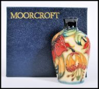 A Moorcroft ceramic vase tube lined decorated with flowers complete in original box C98 mushroom