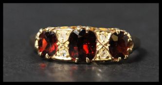 An early 20th century hallmarked 18ct gold garnet and diamond ring set with three oval cut garnets