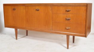 A 1970's retro Danish influenced teak wood sideboard being raised on tapering legs with a series
