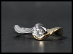 An 18ct white and yellow gold solitaire diamond ring having a single diamond in a contemporary