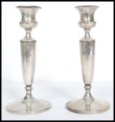 A silver hallmarked pair of candlesticks raised on terraced bases having tapering stems and single