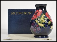 A Moorcroft ceramic vase tube lined decorated with flowers in the Anemone Blue pattern complete in