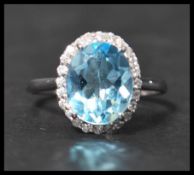 A 925 silver ring set with a large pale blue stone surrounded by a halo of CZ. Weight 3.5g. Size Q.