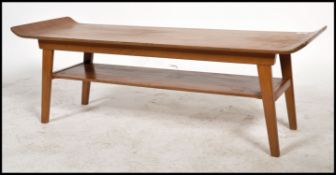A Vintage retro teak wood mid century coffee table raised on shaped legs with under mag shelf, the
