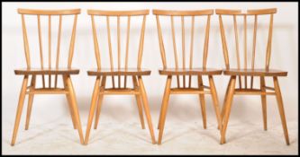 A set of 4 mid century retro Ercol dining chairs being raised on turned legs with stretchers, saddle