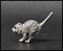 A cast sterling silver figure of a cat with emerald green eyes. Measures 4cms. Weight 13g.