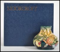 A Moorcroft ceramic vase tube lined decorated with flowers complete in original box C2001 sheild
