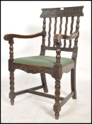 An early 20th century oak carver armchair being raised on bobbin turned supports with stretchers.