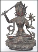 A 19th century cast metal figure of a seated eastern Tibetan Buddha raised on a stylised lotus