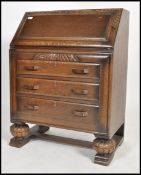 A 1930's Art Deco oak bureau desk raised on ball feet with a bank of drawers under a fall front