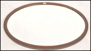 A large early 20th century oak framed oval wall mirror. The large oversized mirror with central