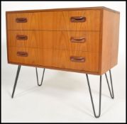 A vintage 20th century teak G-Plan chest of 3 drawers being raised on hairpin legs ( label to inside