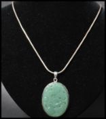 A 925 silver pendant necklace strung with a carved jade pendant with dragon decoration strung on a