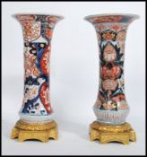 A near pair of late 19th Century Japanese Oriental Imari flared neck floral design vases raised on