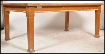 A large early 20th century solid oak Air MInistry type school library table being raised on square