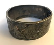 A  hallmarked silver aesthetic movement bangle bracelet decorated with oriental ships and birds.