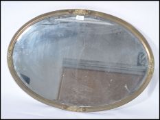 A late 19th century Arts and Crafts brass oval; framed wall mirror, the frame decorated in relief