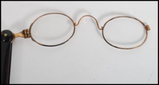 A pair of early 20th century lorgnettes folding opera glasses having yellow metal glasses with a