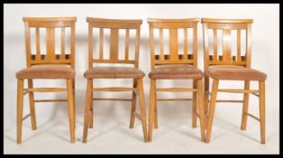 A set of 4 20th century beech wood chapel chairs being raised on turned legs with overstuffed