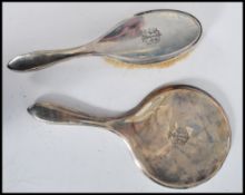 A silver hallmarked matching brush and mirror with monograms. The mirror having a bevelled glass