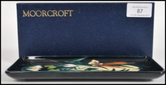 A Moorcroft ceramic pin tray of rectangular form tube lined decorated with flowers complete in