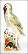 A Royal Crown Derby paperweight, Green Woodpecker, silver stopper and stamped to base. Measures 17